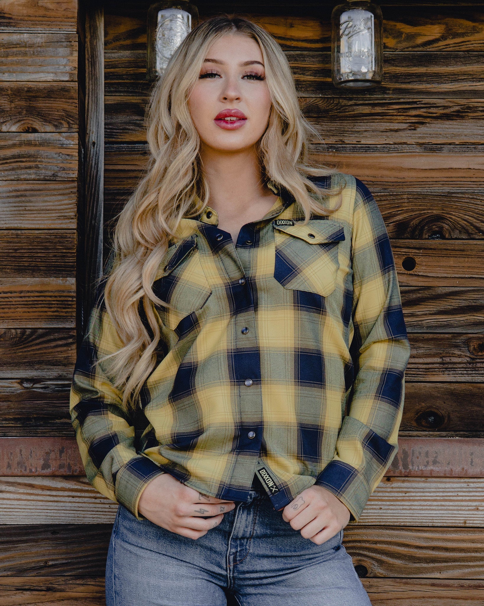 Woman in front of wood cabin wearing Women's The Banquet Flannel