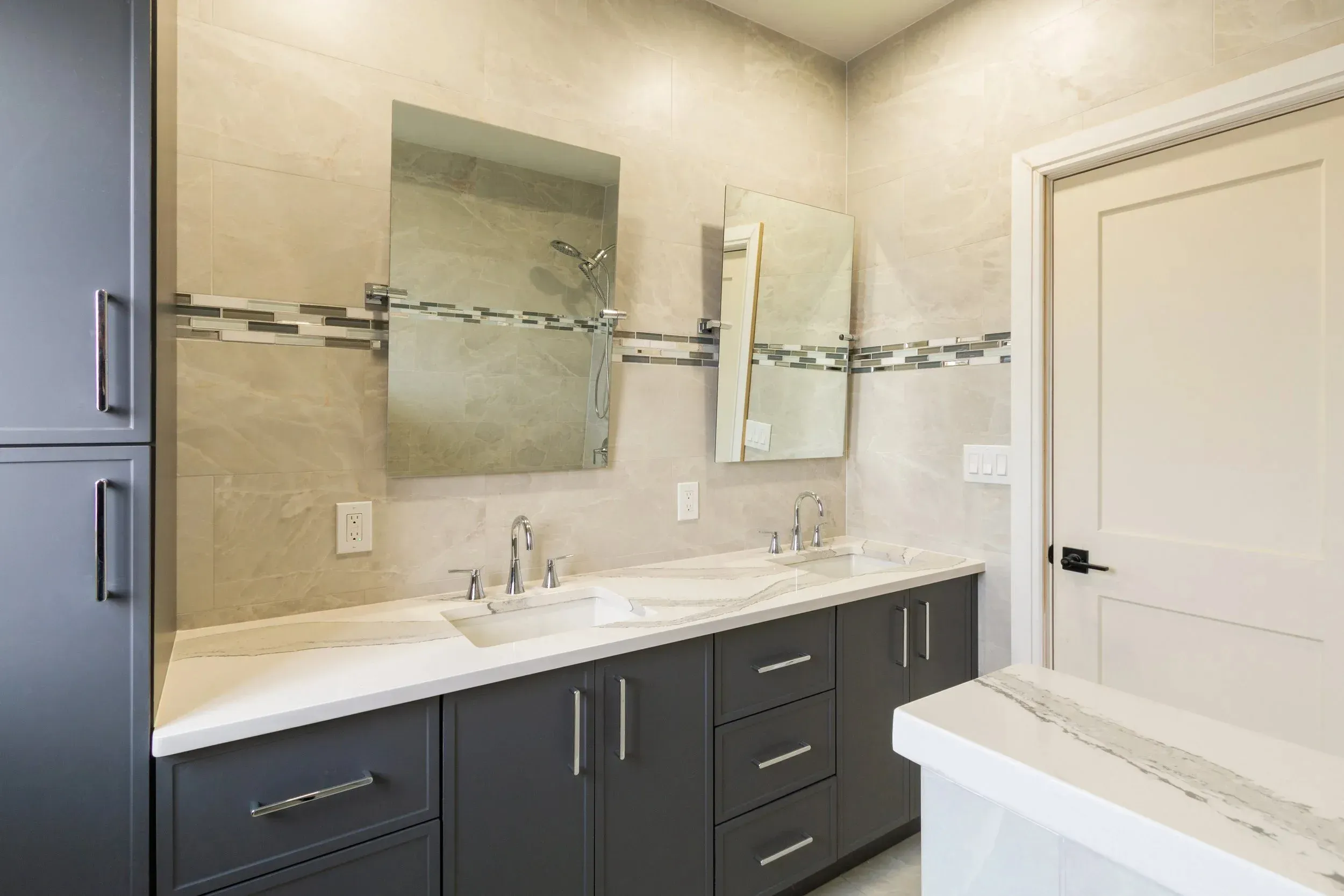 Modern bathroom with double sinks, large mirrors, and elegant tile accents