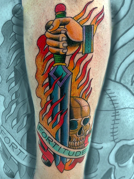 A bold American Traditional tattoo of a hand gripping a dagger surrounded by flames, positioned next to a skull with a "Fortitude" banner at the base.