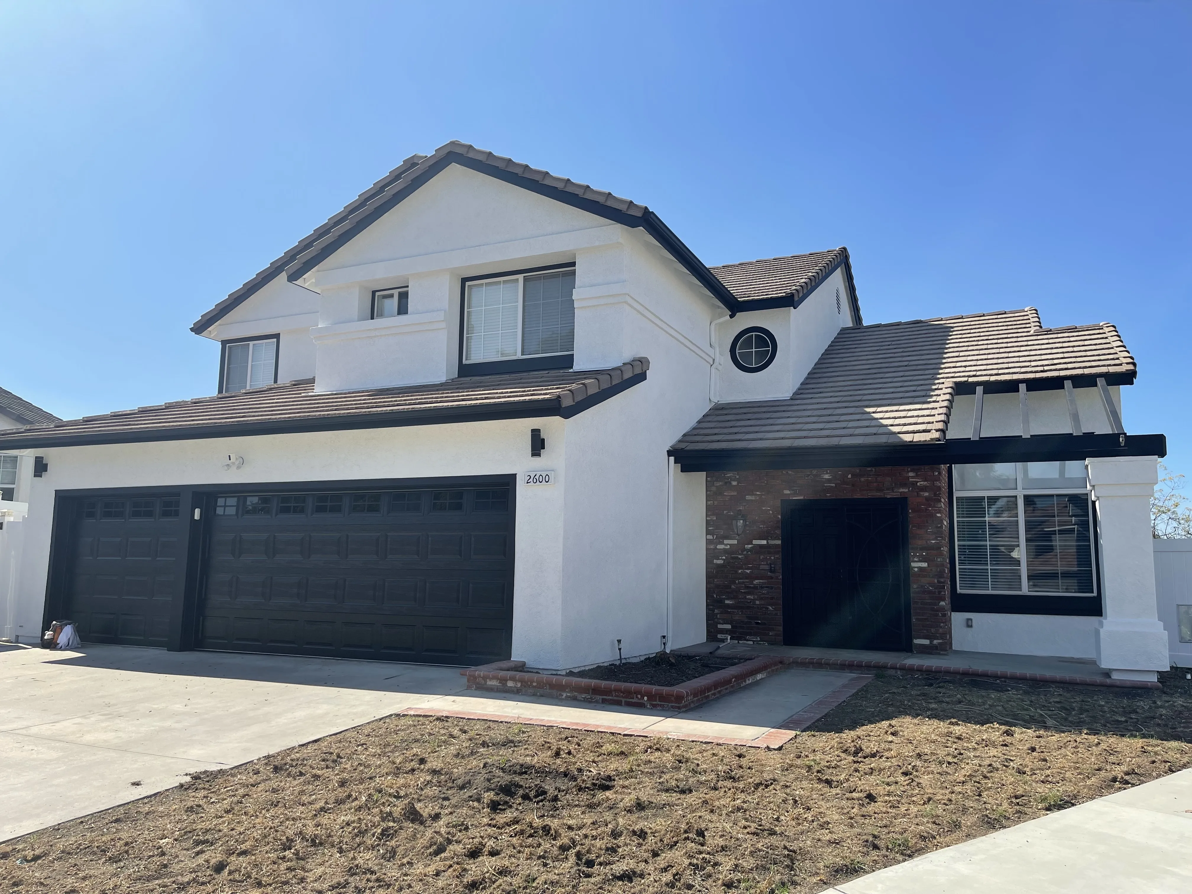 Freshly painted house exterior in Riverside, CA, illustrating professional painting work with tools in view.