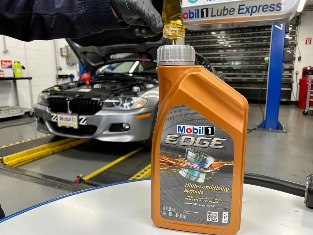 Bottle of high mileage motor oil being poured into an engine