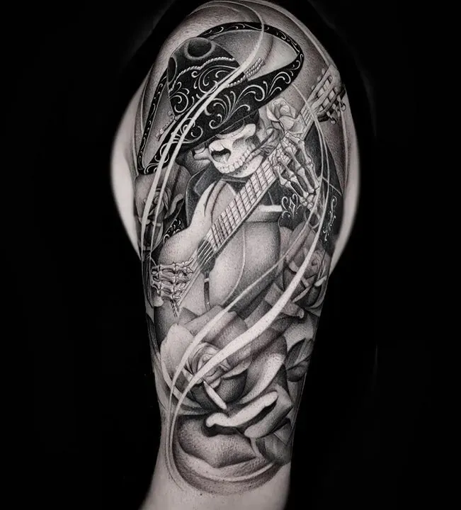 Black and gray realistic tattoo of a skeleton wearing a sombrero and playing a guitar with roses.
