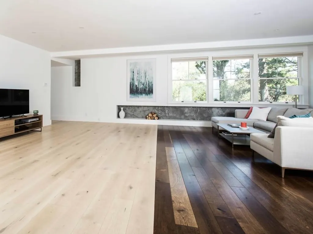 Homeowner comparing light and dark flooring samples in a Greensboro living room