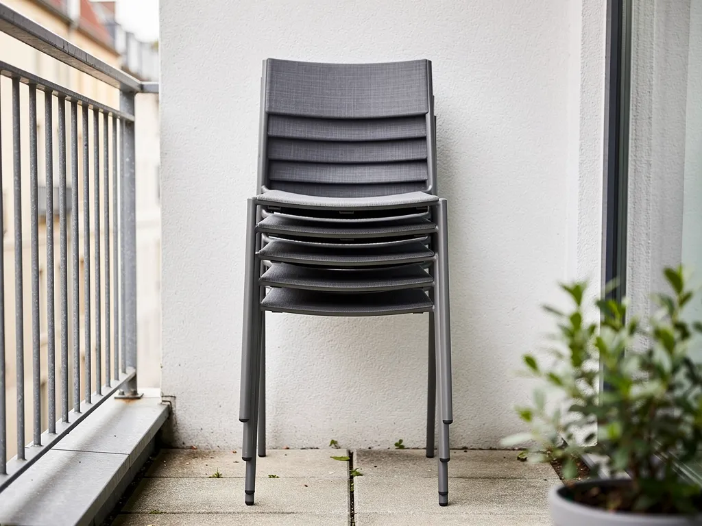Stackable outdoor chairs vertically stacked on a small patio, space-saving furniture storage solution