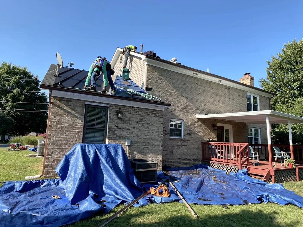 Roofing technician inspecting shingles during a rooftop evaluation