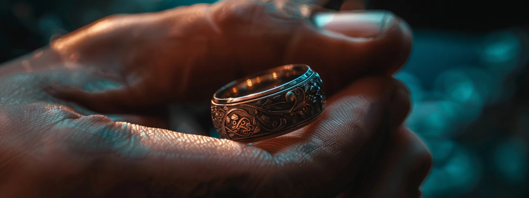 a hand holding a gleaming stainless steel wedding ring, engraved with intricate designs, reflecting the light.