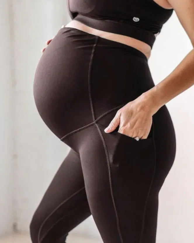 Close up view of woman wearing brown leggings over large baby bump