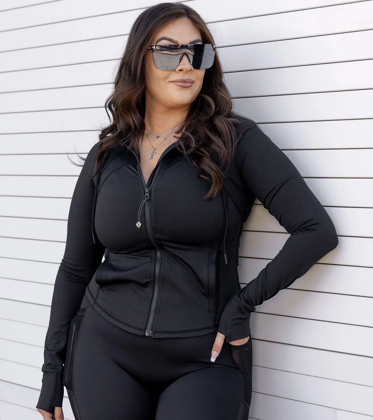 Woman in form-fitting black athletic jacket with dark sunglasses