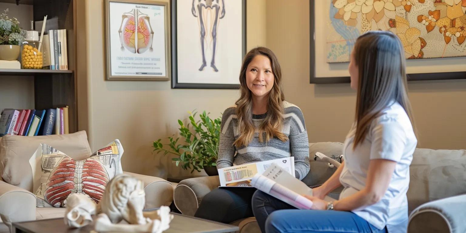 Two women engaged in a consultation about joint pain management in a comfortable office setting, with anatomical art on the walls and a cozy decor featuring educational materials.