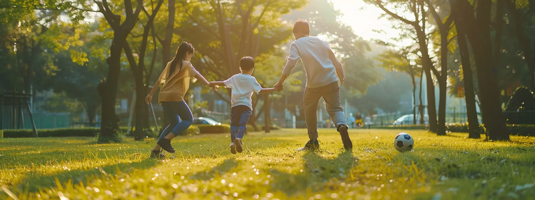 a family playing soccer in the park together.