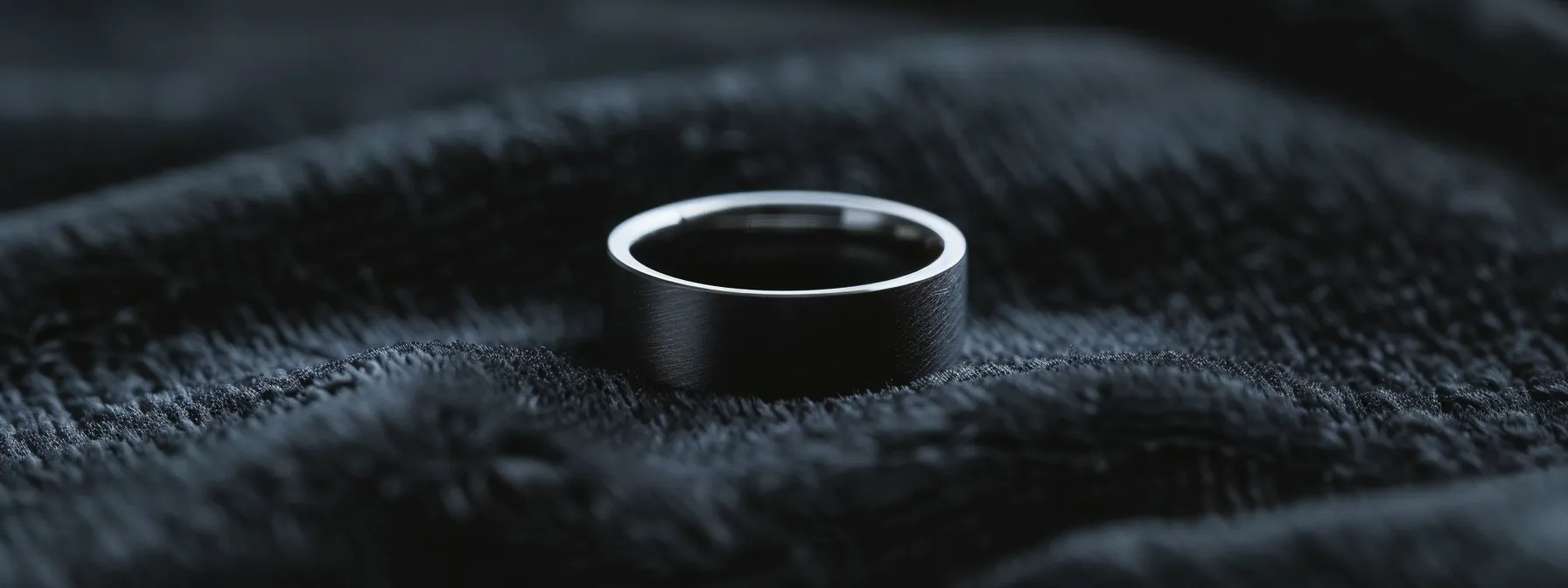 a sleek and modern titanium men's wedding ring displayed on a black velvet background, highlighting its unique combination of strength and lightness.