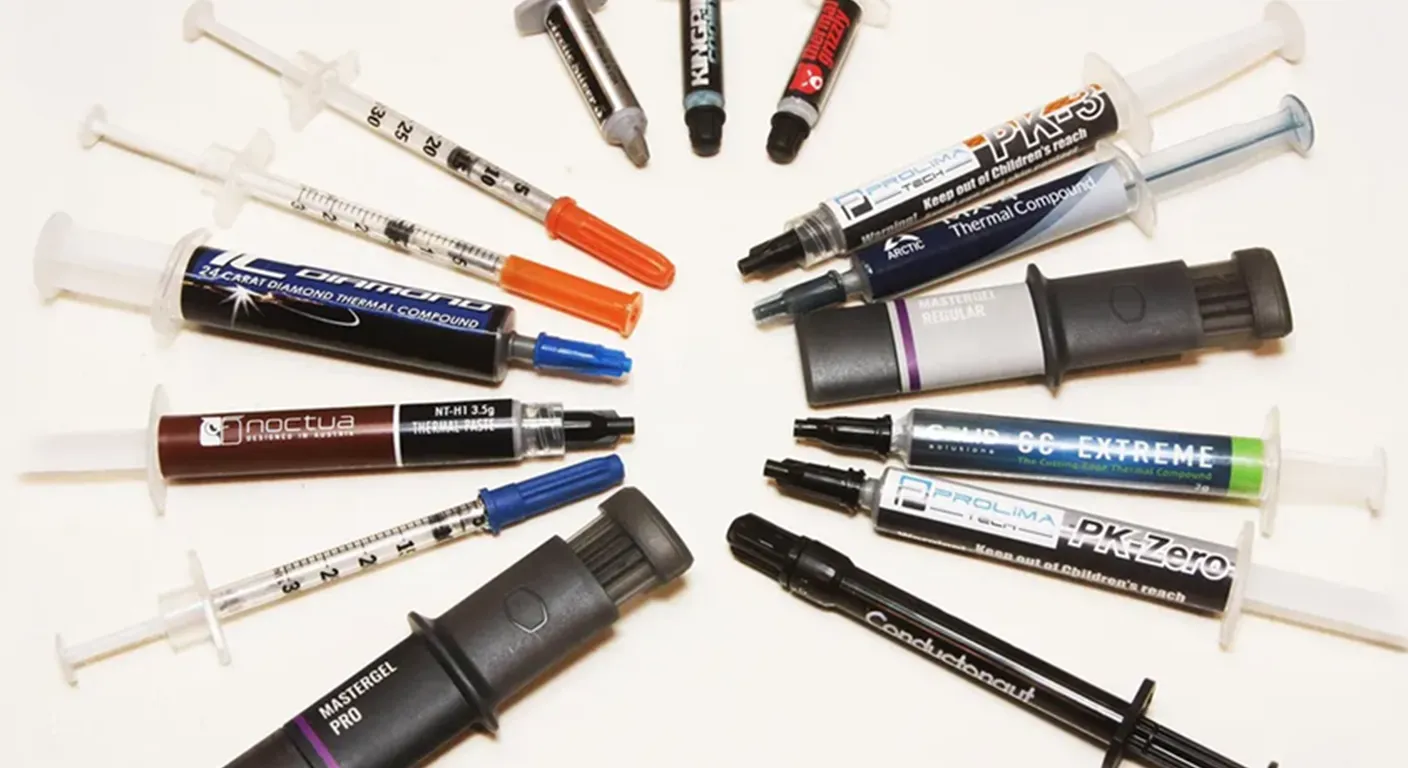 Assorted thermal paste syringes from multiple brands arranged in a circle on a white background, including Noctua, Arctic, MasterGel, and Prolimatech compounds.