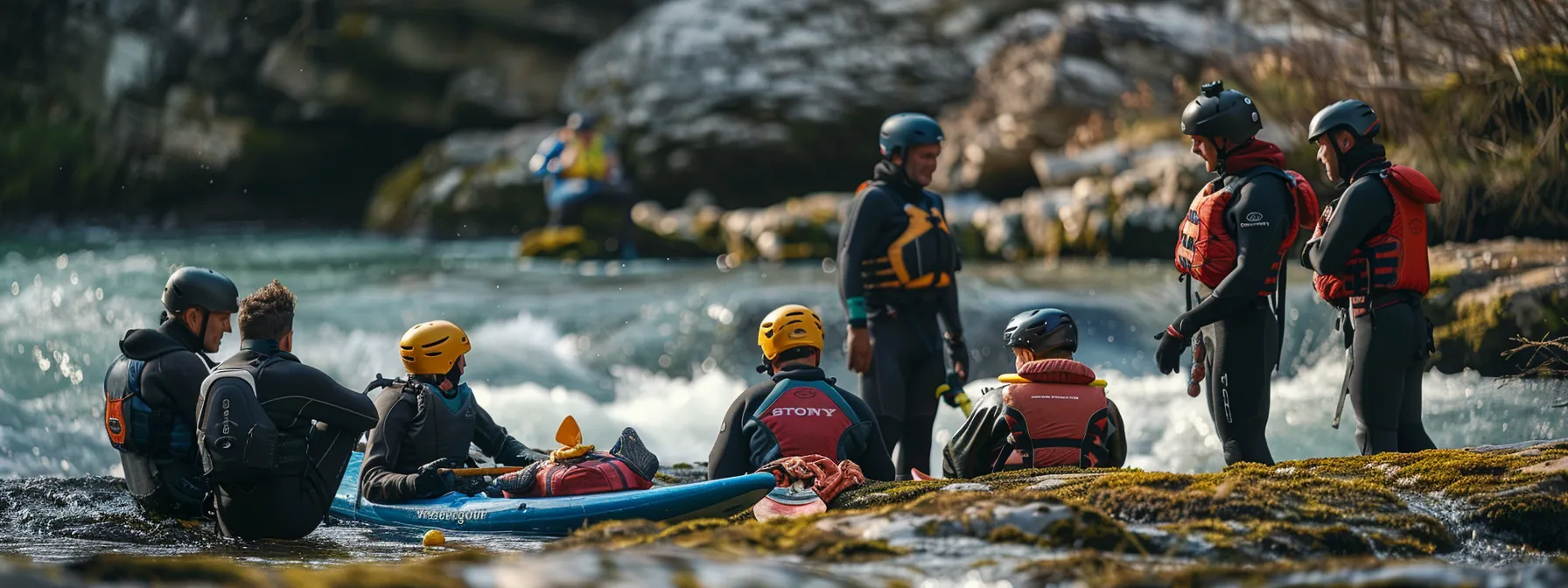 a group of people in wetsuits and helmets gather around a stack of paddles and life vests near a rushing river.