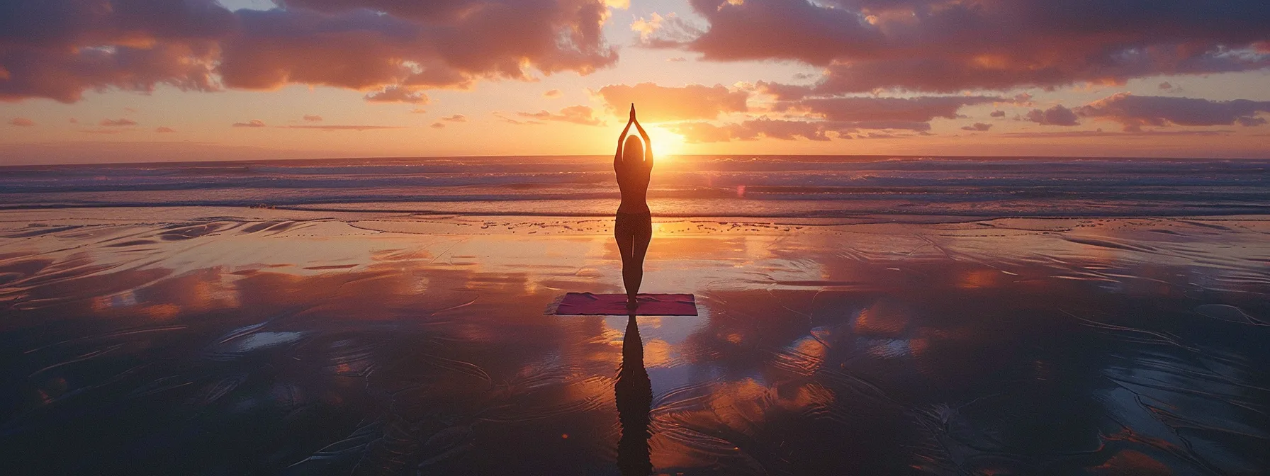 a woman practices yoga on a peaceful beach at sunrise.