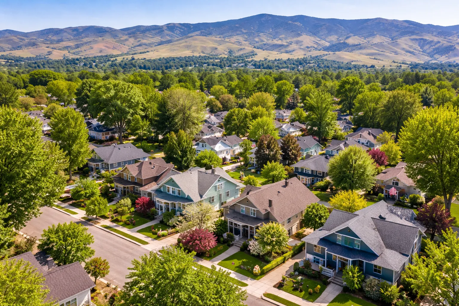 Aerial view of a tree-lined Boise, Idaho neighborhood featuring well-maintained single-family homes with the Boise foothills in the background. Aerial view of a tree-lined Boise, Idaho neighborhood featuring well-maintained single-family homes with the Boise foothills in the background.