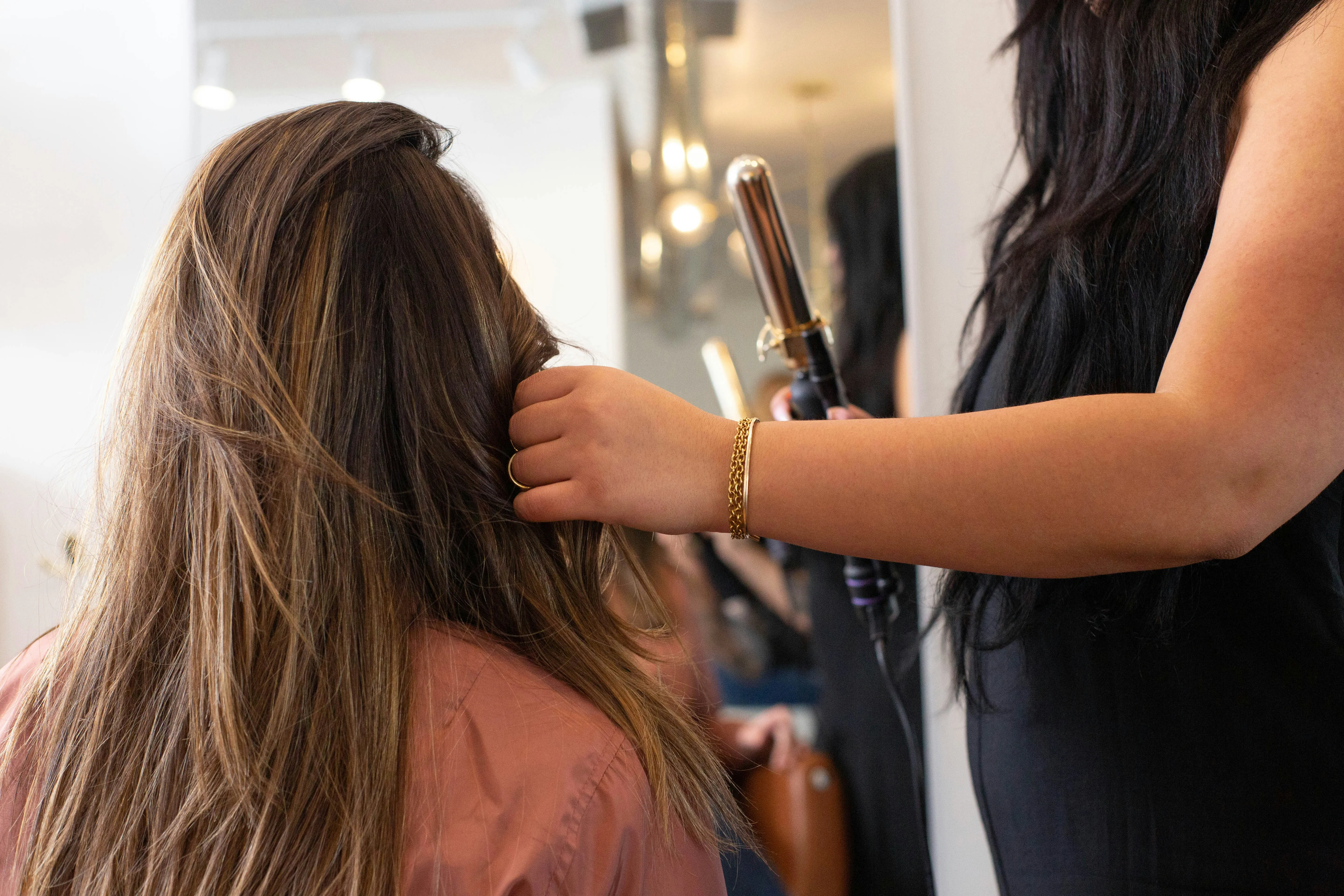 Stylist curling hair with a hot iron after weft extension application. Stylist curling hair with a hot iron after weft extension application.