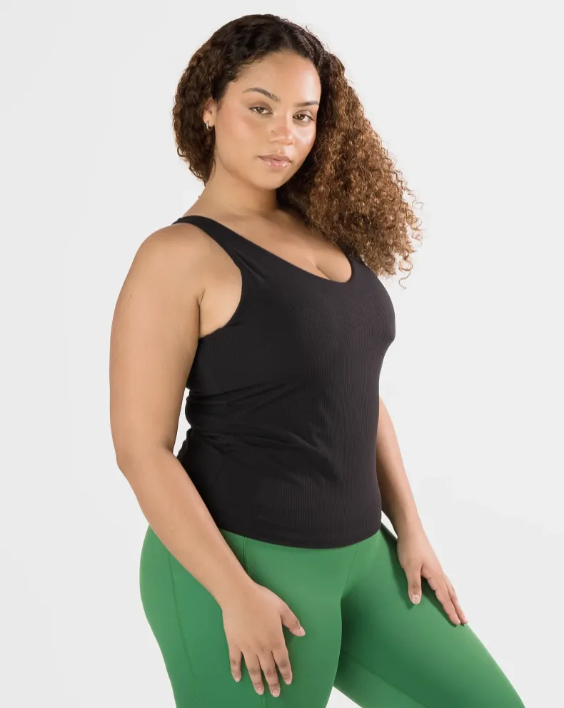 Woman wearing black top and green leggings from the Ribbed Fabric collection
