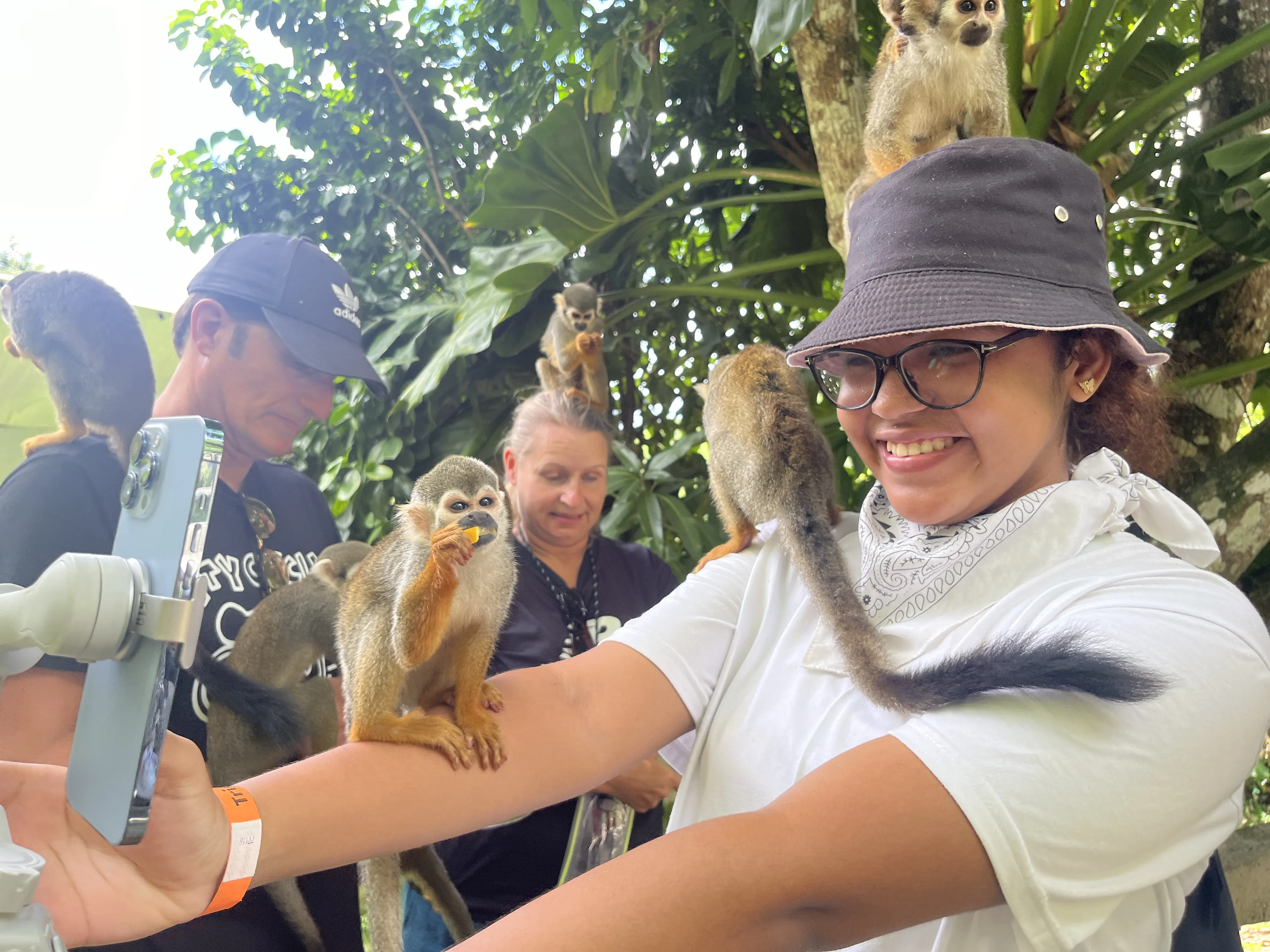 Visitor smiling while taking a selfie with squirrel monkeys on her head and shoulders at Monkey Land in Punta Cana