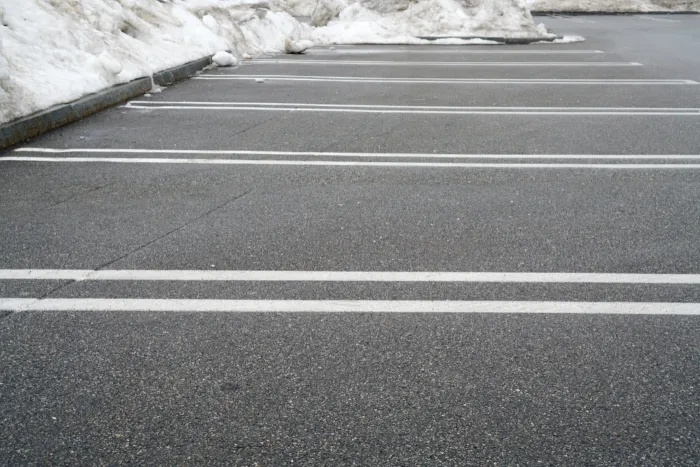 Snow plow clearing a parking lot in Amherst, NY after a snowfall, illustrating reliable snow plowing services. Snow plow clearing a parking lot in Amherst, NY after a snowfall, illustrating reliable snow plowing services.