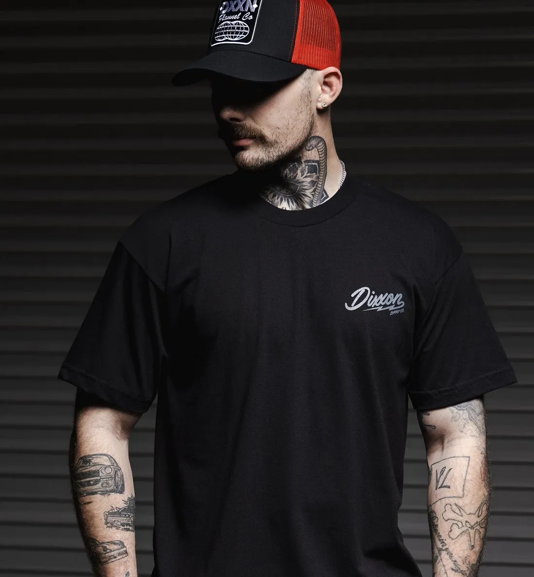 Man standing in front of a garage wearing a Dixxon hat and black Dixxon t-shirt