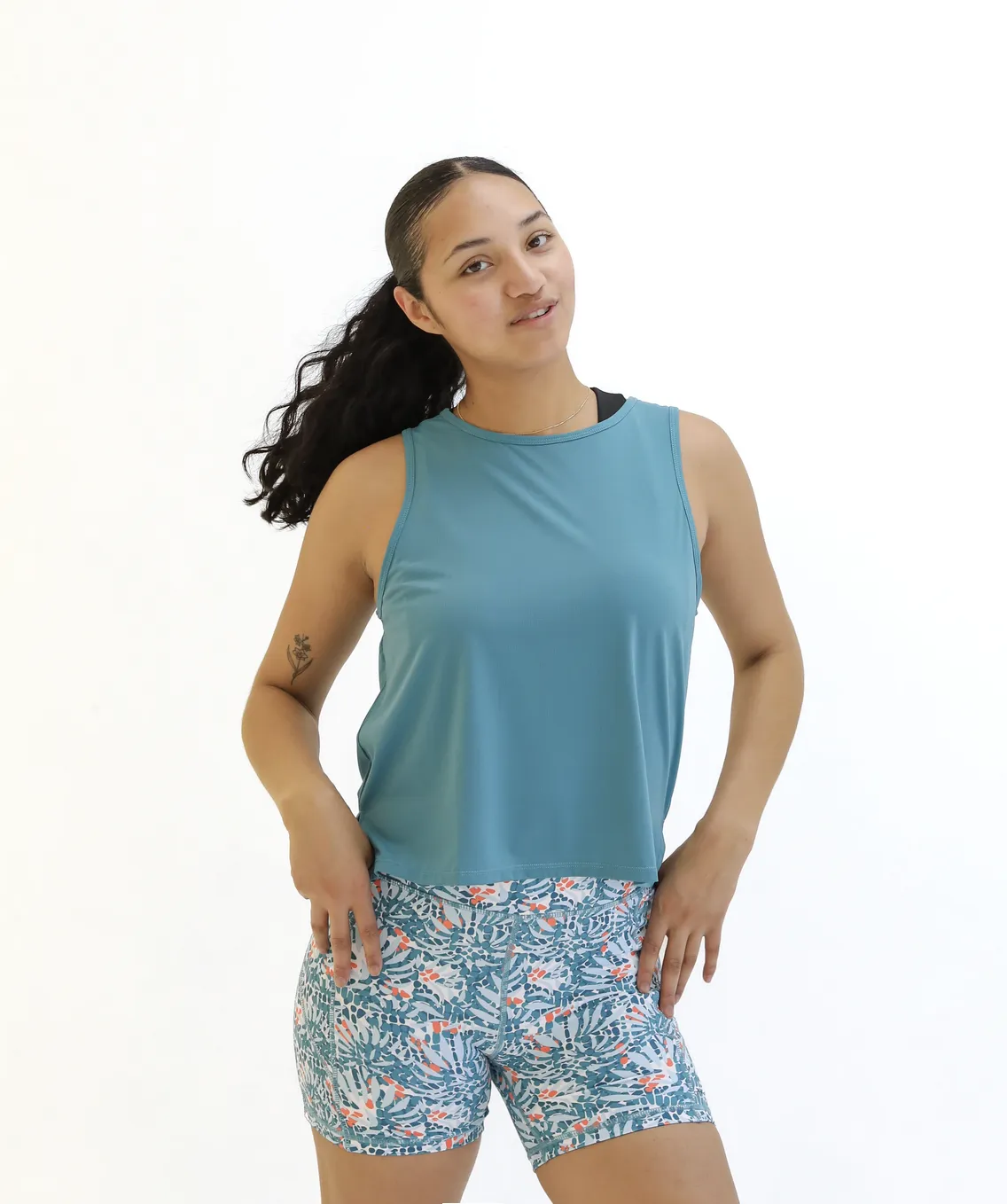 Woman with hands on her hips wearing Breathetech Open Back Tank - Harbor and multi-color athletic shorts
