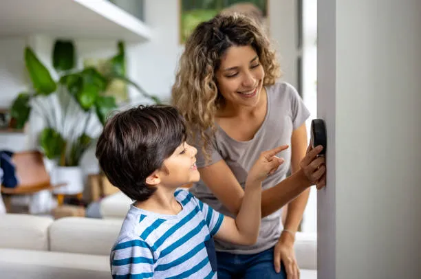Homeowner and child adjusting a thermostat, illustrating common AC issues that may require emergency repair.