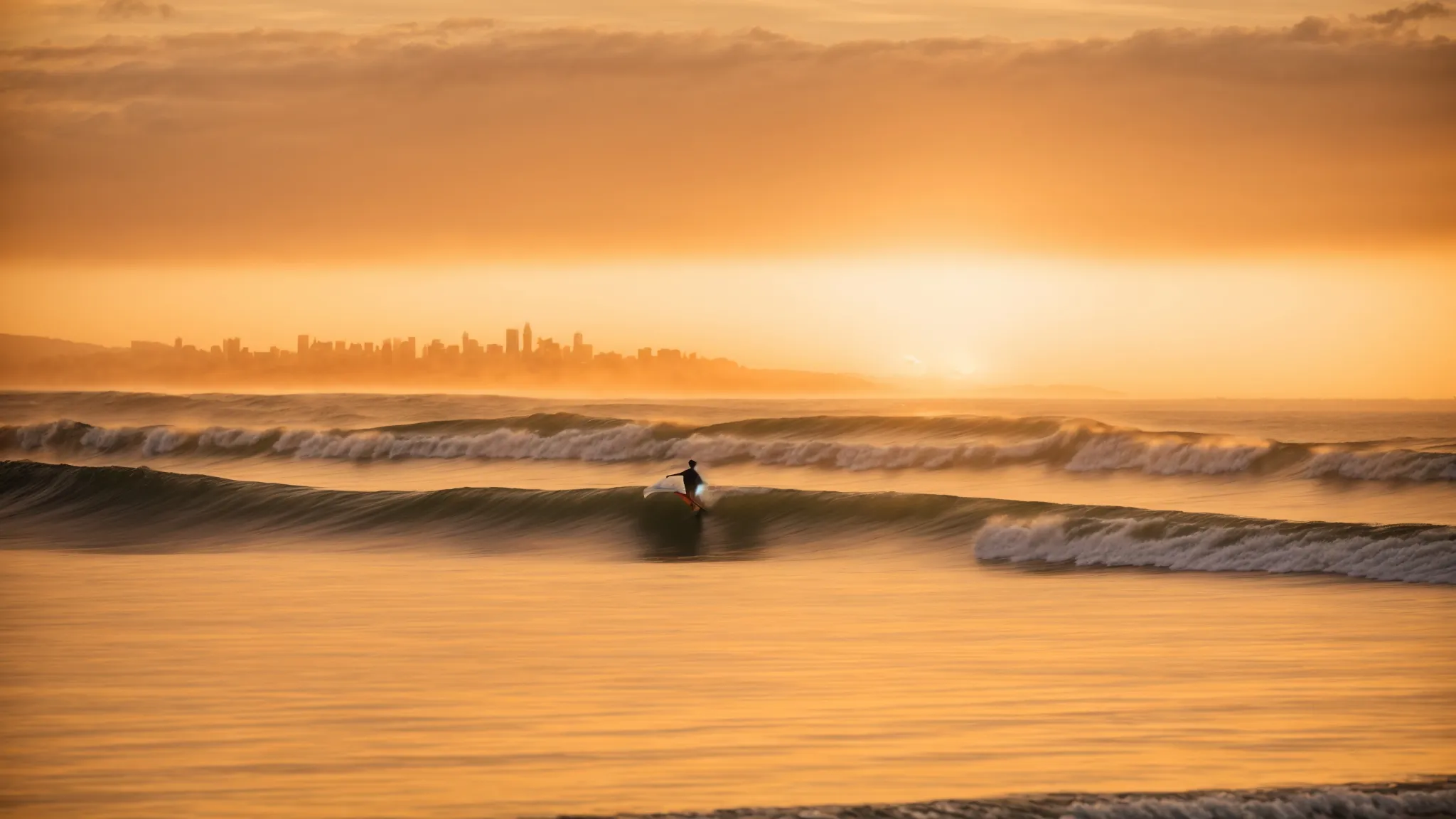 a surfer patiently waits on the crest of a gentle wave, looking towards a distant skyline of san diego under a golden sunset.
