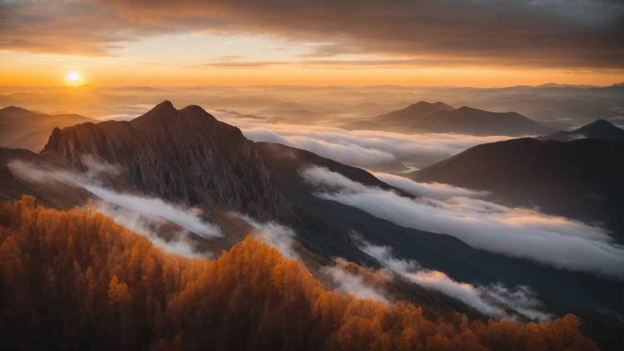 a sunset view from a mountain top, casting a golden hue over the clouds below.