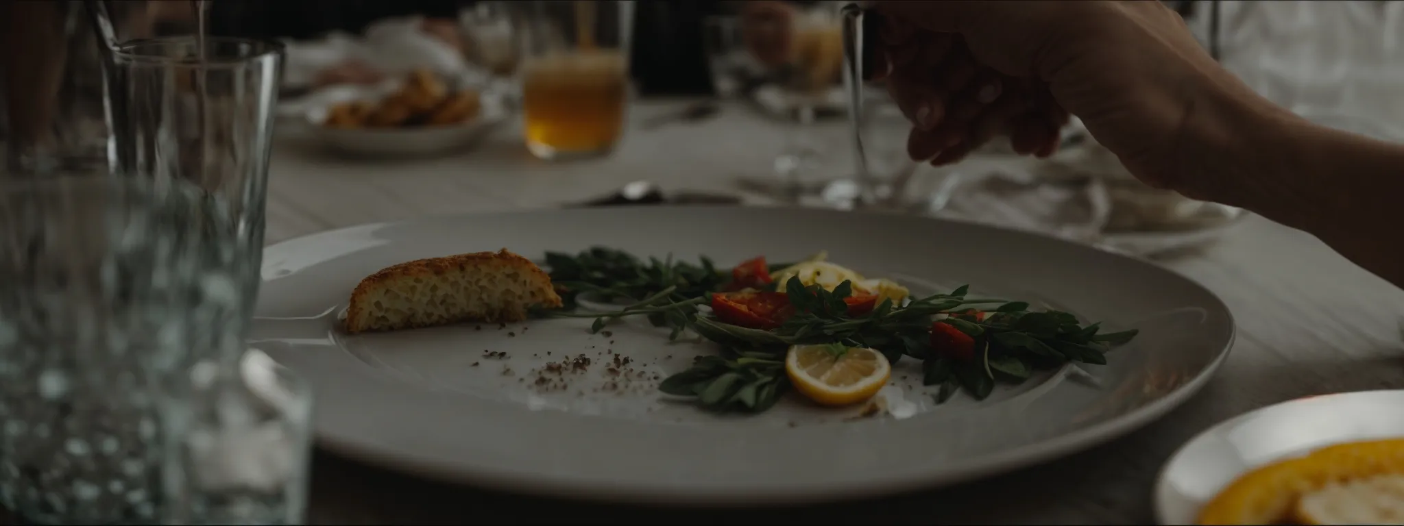 a person pensively examines the contents of their nearly empty plate at a dining table.