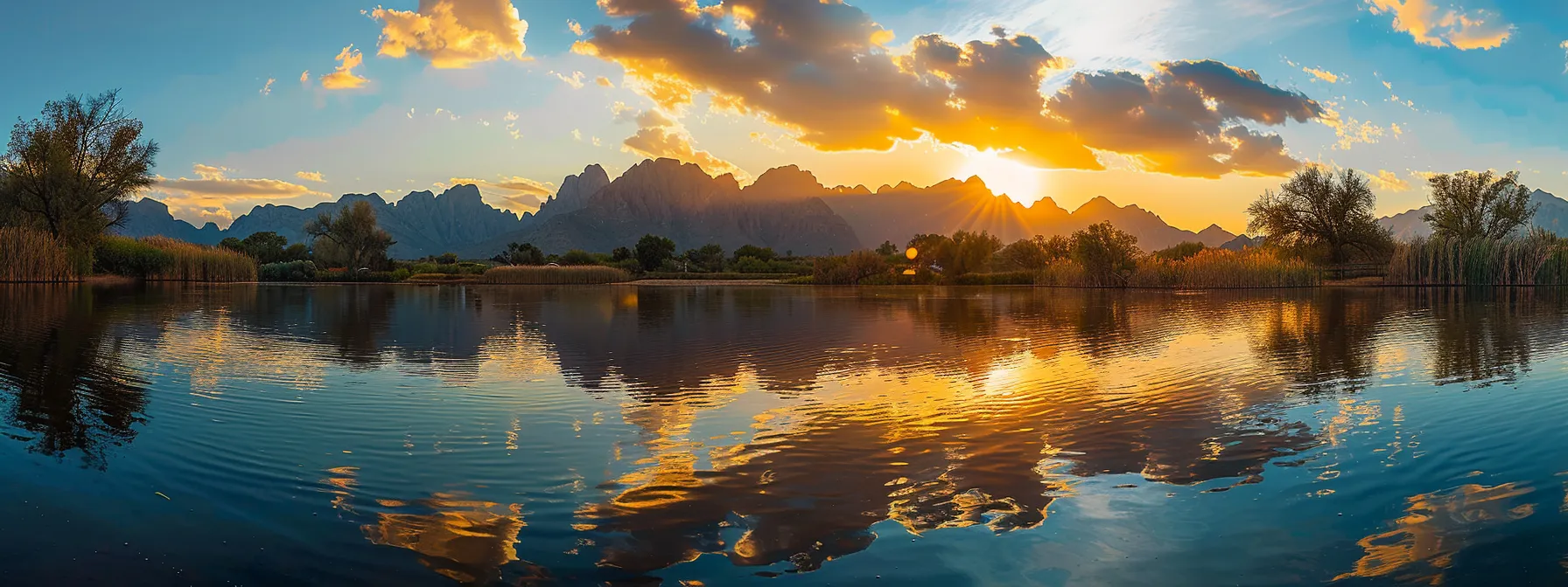 a breathtaking sunset casts golden hues over a tranquil lake, with silhouettes of distant mountains reflecting perfectly on the glassy water surface.