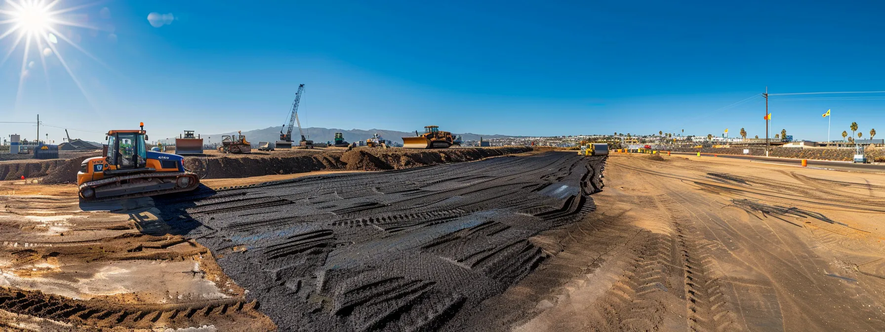 a dynamic urban construction site in san diego showcases contractors skillfully operating advanced asphalt grading machinery, surrounded by intricate drainage systems designed to tackle the region's unique soil and climate challenges, under a clear blue sky.