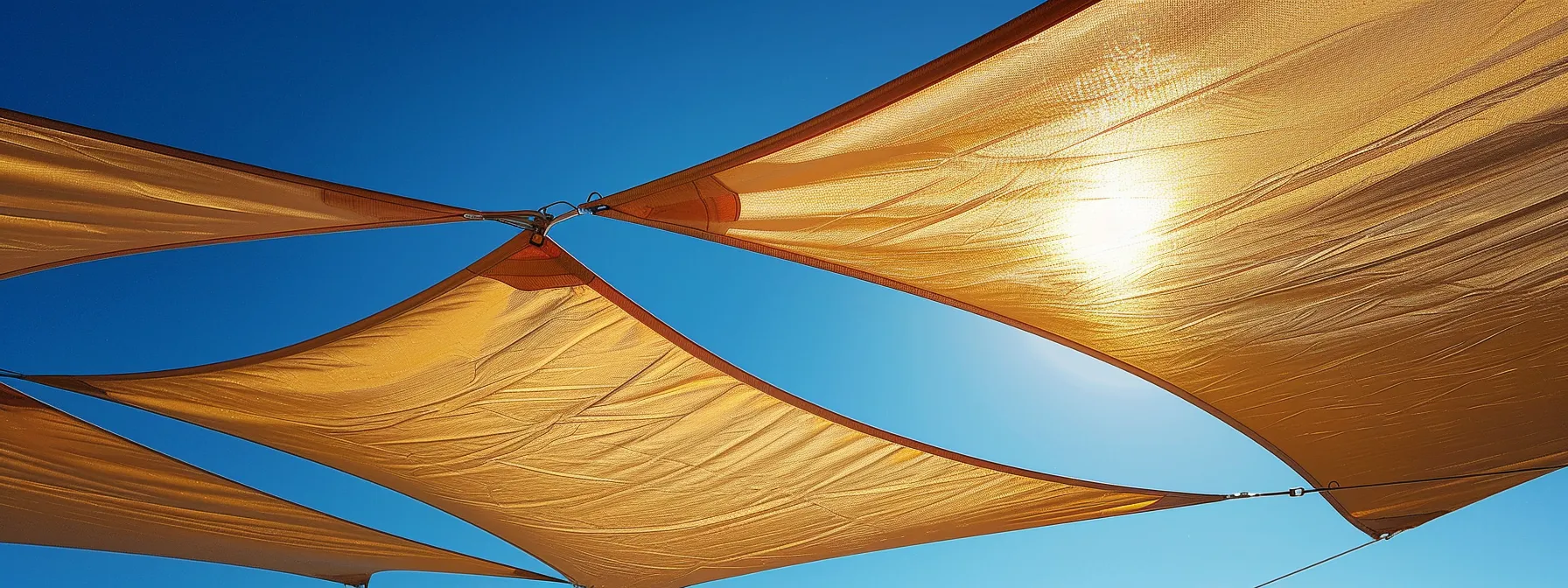 a pristine sail shade, gently billowing in the winter breeze against a backdrop of a clear blue sky, accentuates the importance of regular maintenance with glimmers of sunlight reflecting off its clean, vibrant fabric.