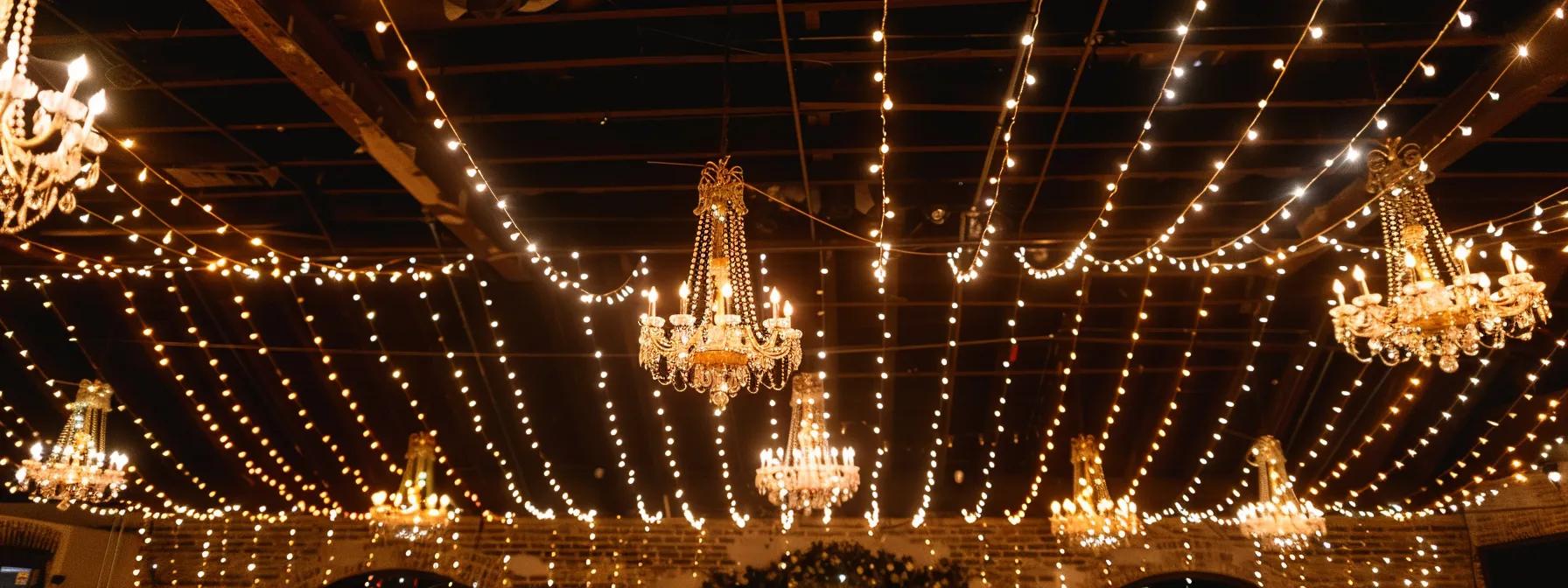 a vibrant event space illuminated by an intricate arrangement of string lights and elegant chandeliers, creating a captivating atmosphere that transitions seamlessly from an intimate dinner setting to a lively dance floor.
