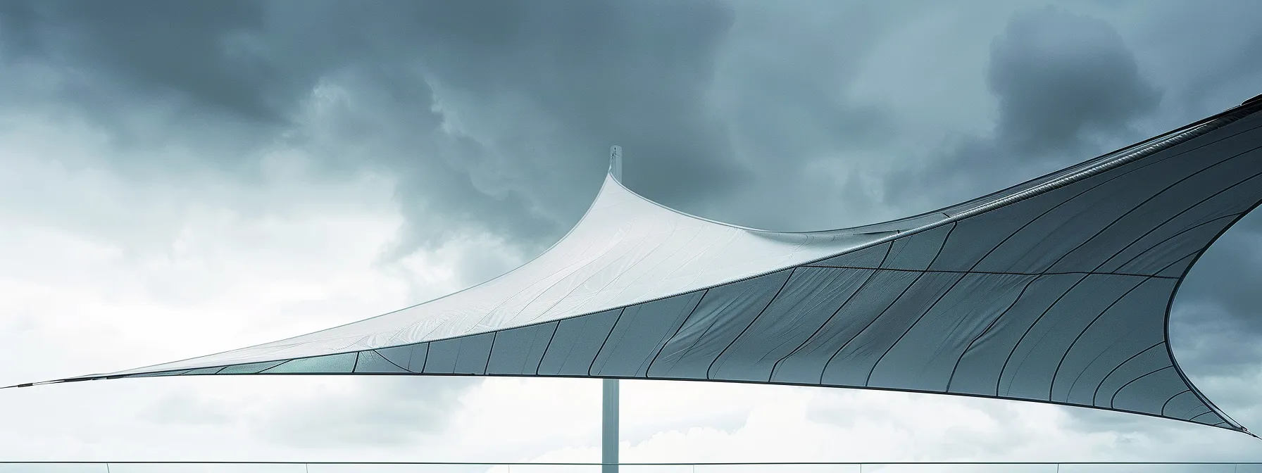 a weather-beaten sail shade, drooping under the weight of accumulated rain, stands resilient against a backdrop of grey winter skies, highlighting the challenges of seasonal weather on outdoor structures.