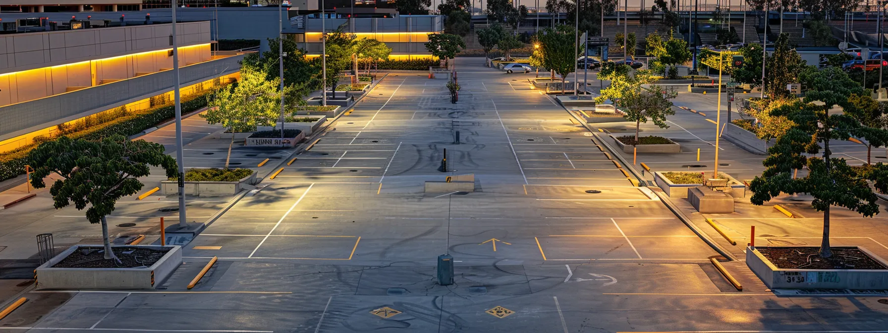 a well-organized urban parking lot in san diego showcases clearly defined parking spaces, highlighted by durable concrete wheel stops that ensure safe and orderly vehicle arrangement under bright artificial lighting.