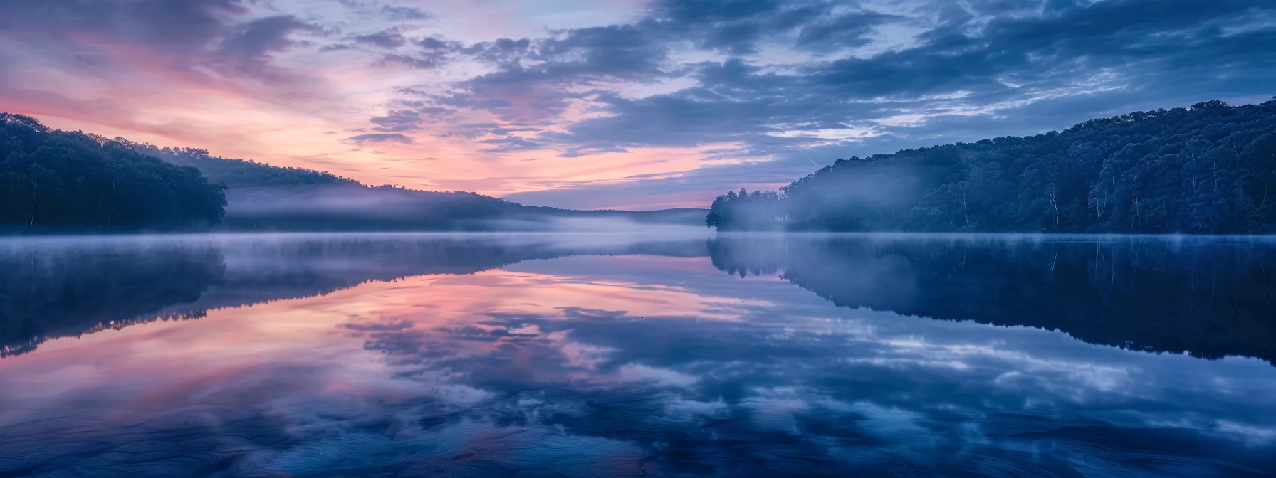 an ethereal landscape unfolds at dawn, where mist gently cloaks a tranquil lake, reflecting the vibrant hues of the sky, creating a serene tableau that captures the essence of natural beauty.