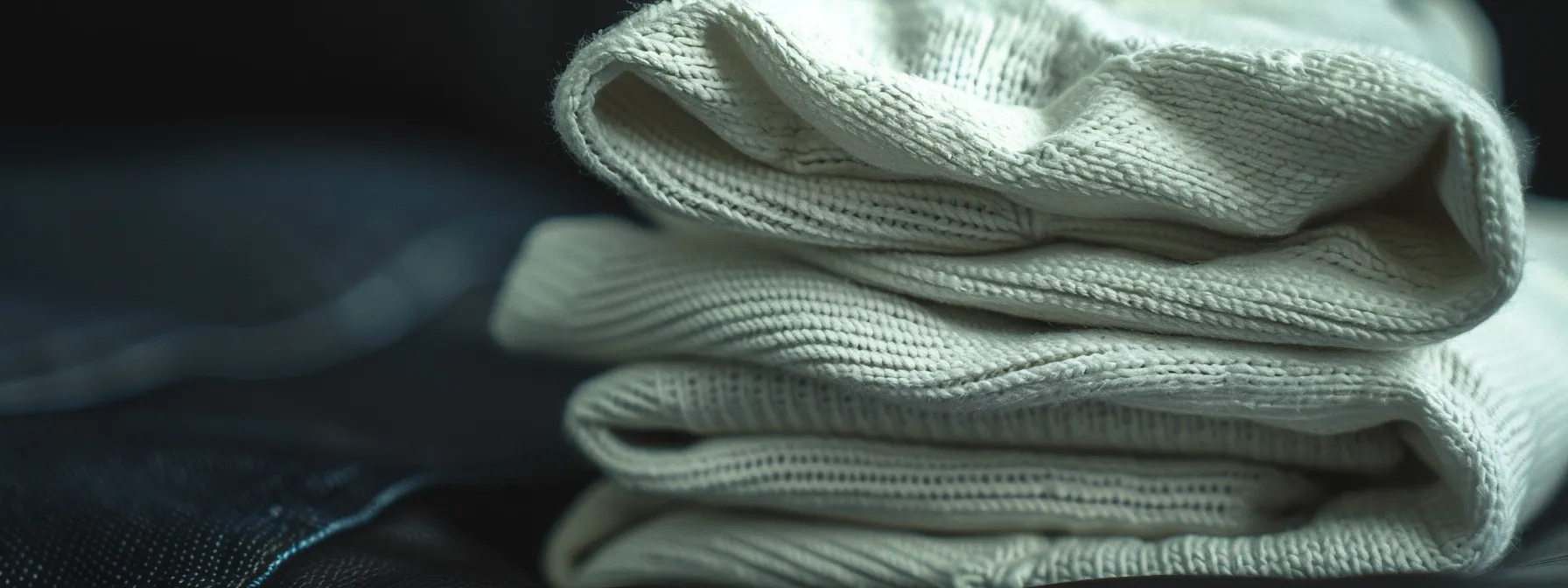 a close-up shot of a stack of crisp white jeans against a dark leather background, showcasing their sleek and stylish design. a close-up shot of a stack of crisp white jeans against a dark leather background, showcasing their sleek and stylish design.