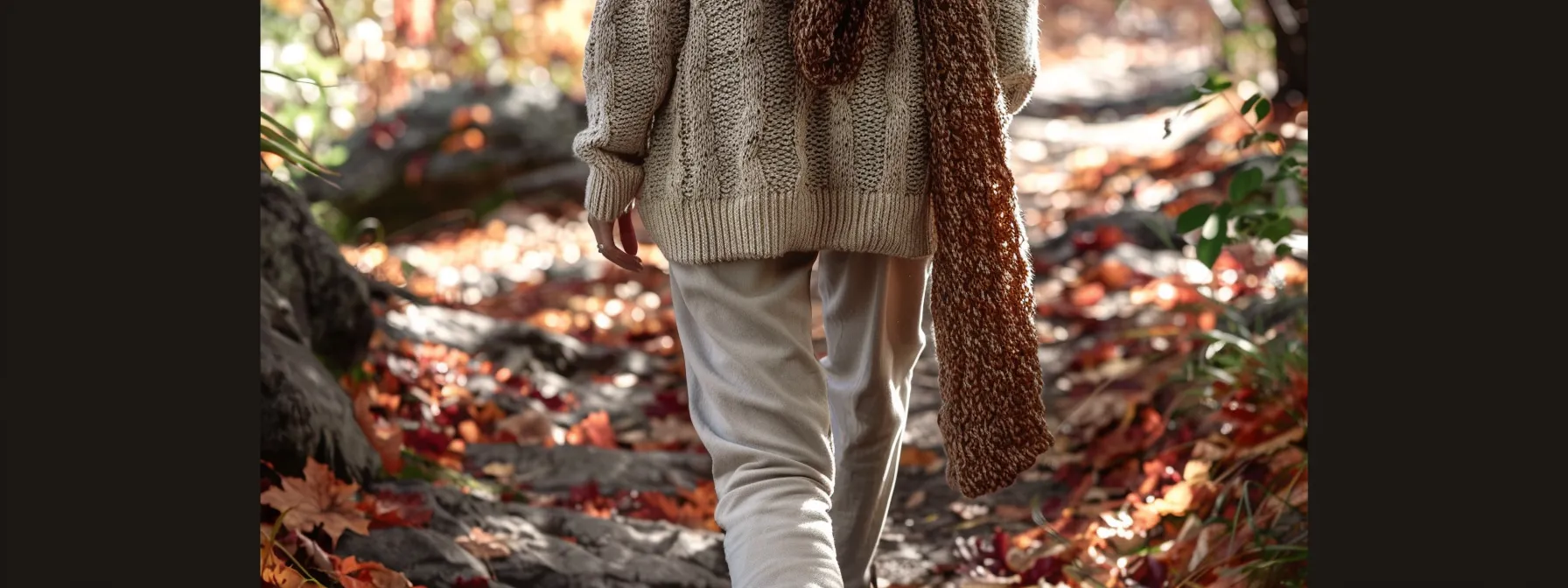 a stylish individual dressed in stacked joggers, layered with cozy sweaters and accessorized with knit scarves and earth tone hues, walking through a picturesque fall park setting. a stylish individual dressed in stacked joggers, layered with cozy sweaters and accessorized with knit scarves and earth tone hues, walking through a picturesque fall park setting.