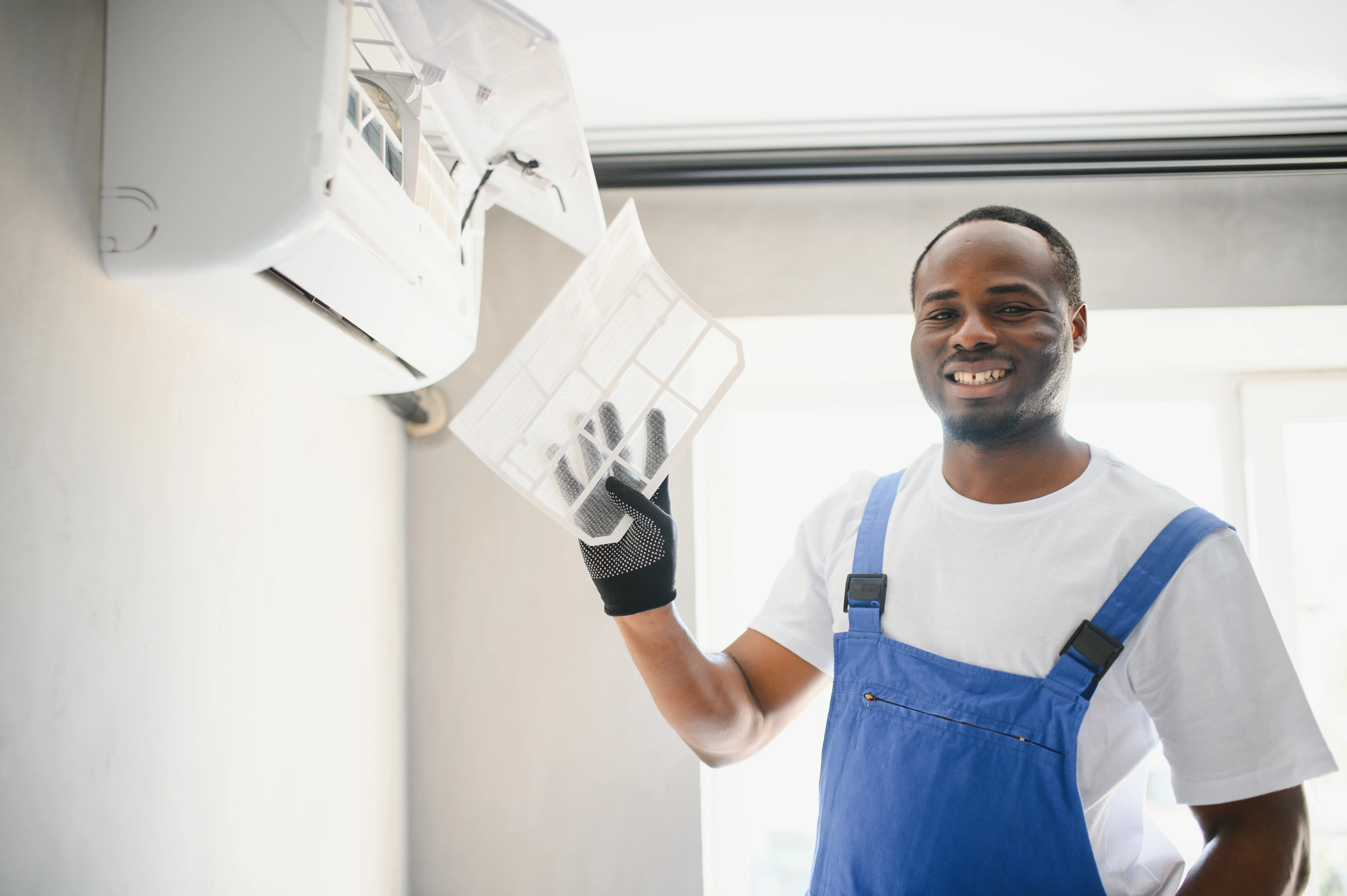 HVAC technician holding a cleaned air conditioner filter, showcasing the importance of regular maintenance and troubleshooting for air conditioning systems. HVAC technician holding a cleaned air conditioner filter, showcasing the importance of regular maintenance and troubleshooting for air conditioning systems.