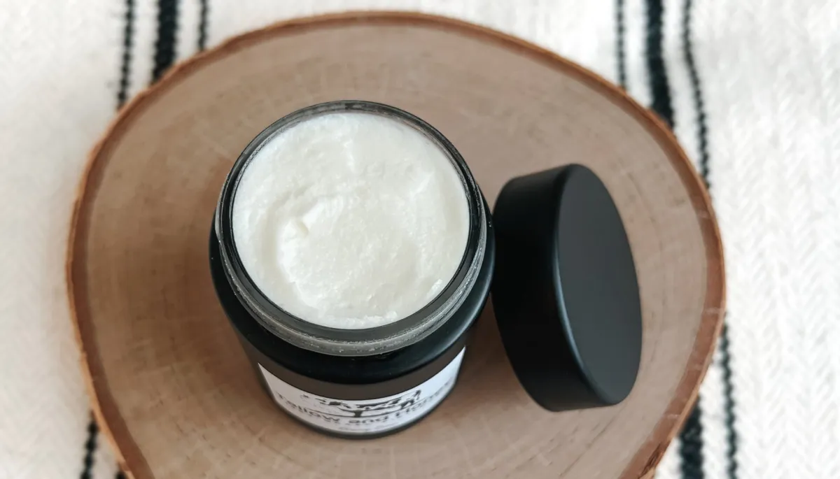 A woman with a thick, clay-like mask applied to her face as an effective oily skin treatment. The mask, which is characteristic of natural tallow skincare products, focuses on the T-zone and cheeks to help balance oils and clarify the complexion.