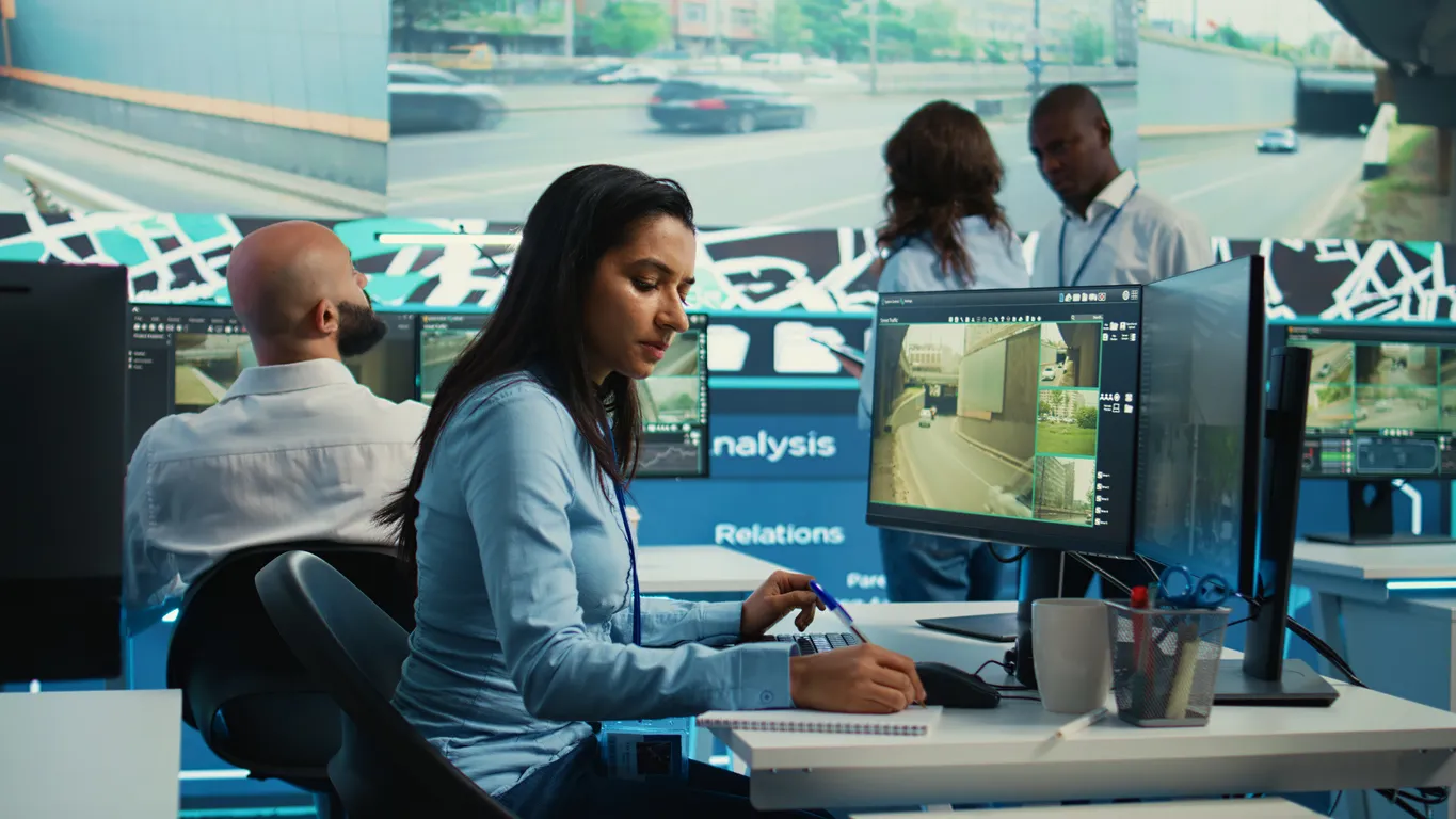 Indian female tracer operator locating digital tracing device in Cardiff office.t location. Control center employee consults satellite map