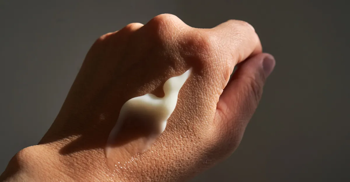 A close-up of a smear of white tallow skincare moisturizer on the back of a person's hand, demonstrating the rich, hydrating texture and natural benefits of tallow for the skin.