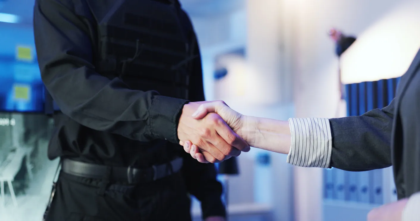 Security, people or shaking hands in control room for welcome, safety team or deal at night. Protection service, guard or gesture in office for late shift, partnership or agreement for surveillance in Chelmsford