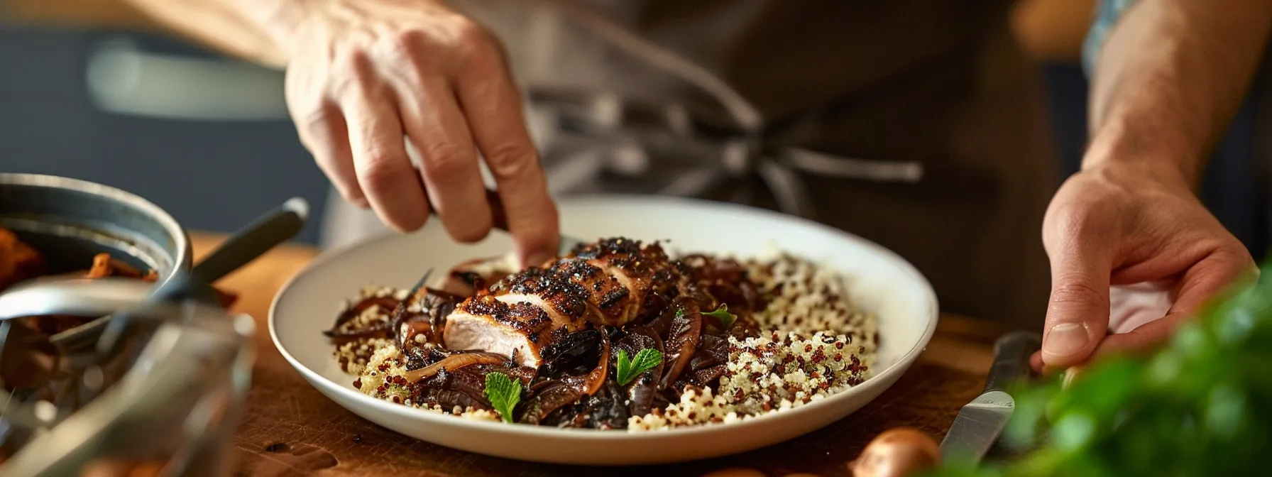 a person meal prepping a plate with quinoa, grilled chicken, caramelized onions, and dark chocolate.