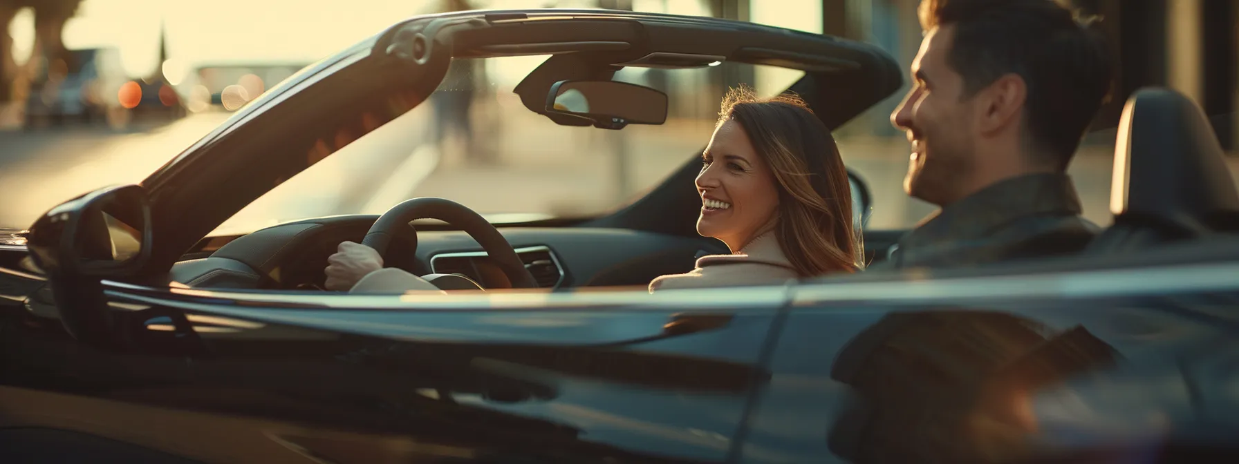 a bright, smiling couple happily test driving a sleek, modern car at the indy auto team dealership.