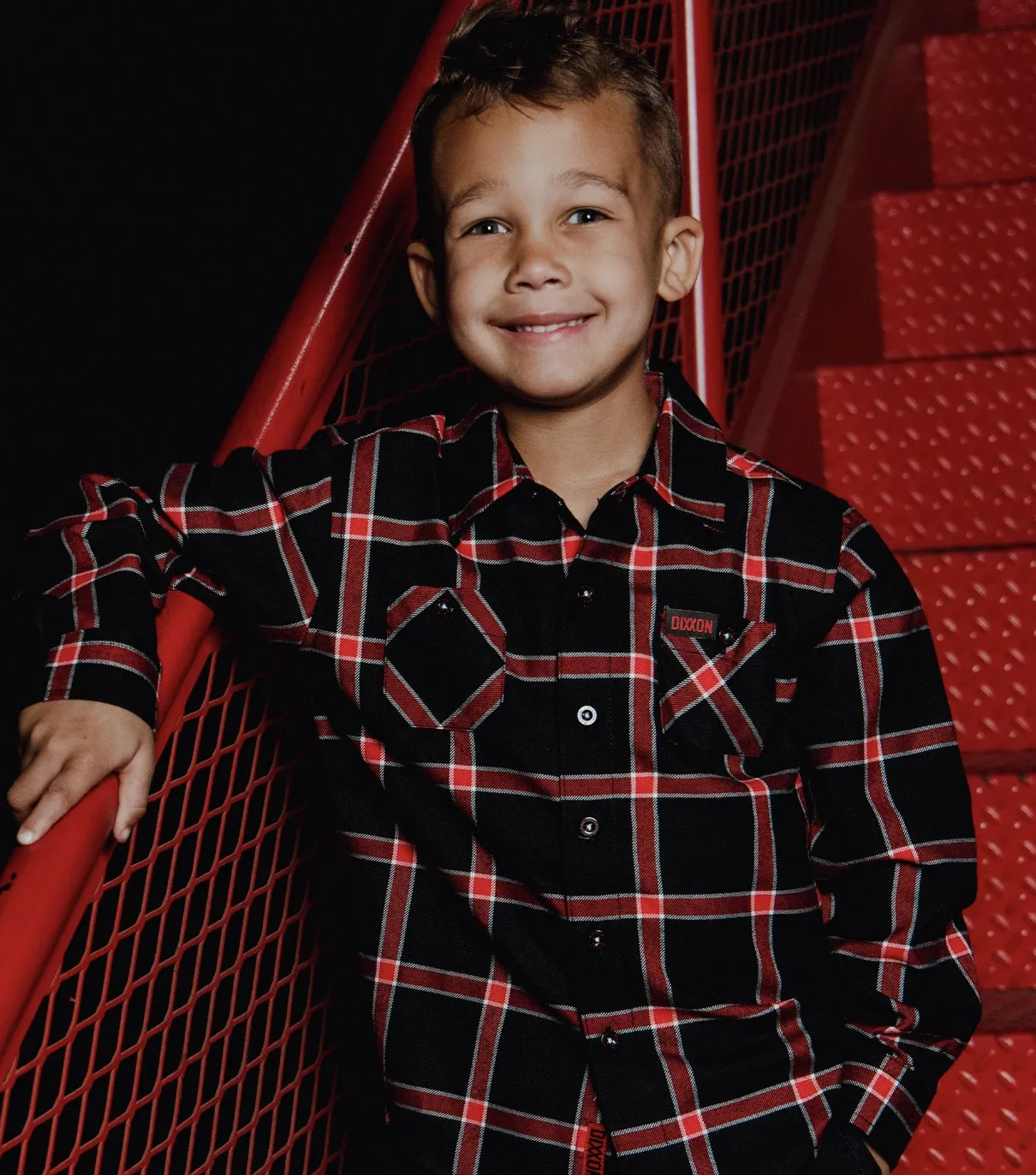 Young boy in front of red background wearing Dixxon Widow Flannel