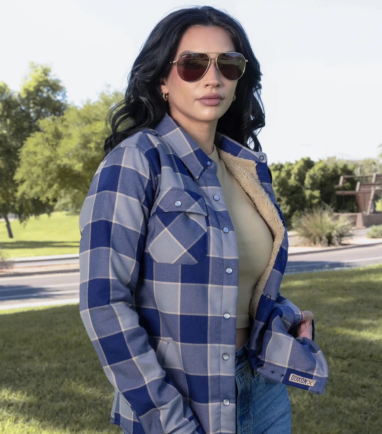 Woman wearing aviator sunglasses wearing tan and blue sherpa lined flannel