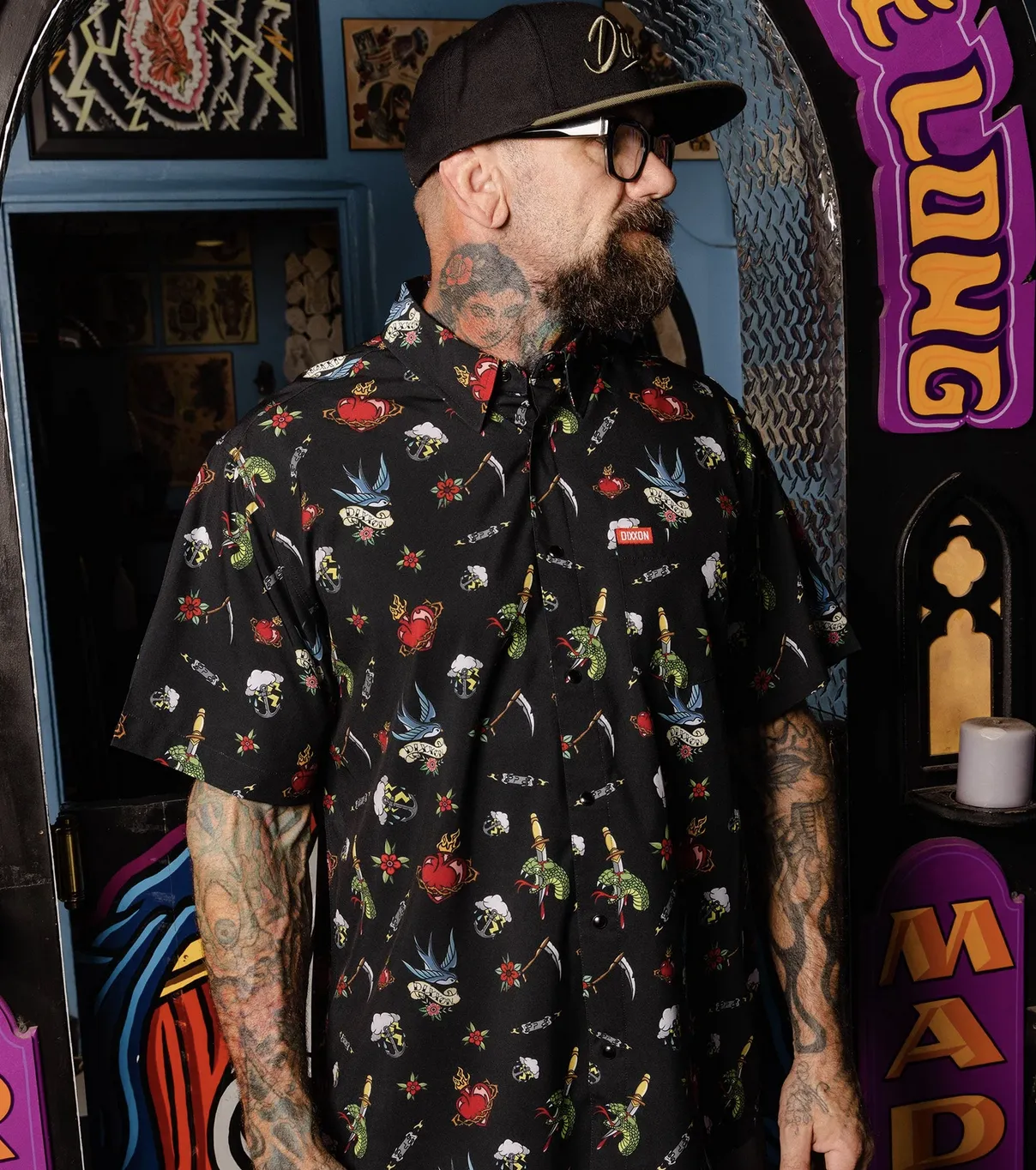 Man in front of colorful industrial background wearing the Dixxon Flasher Party Shirt