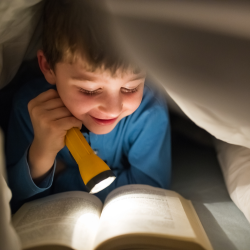 Boy Reading Under Blanket