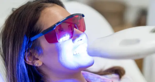A patient receiving a professional laser teeth whitening treatment at Issa Dental to achieve up to 8 shades whiter teeth in one session.